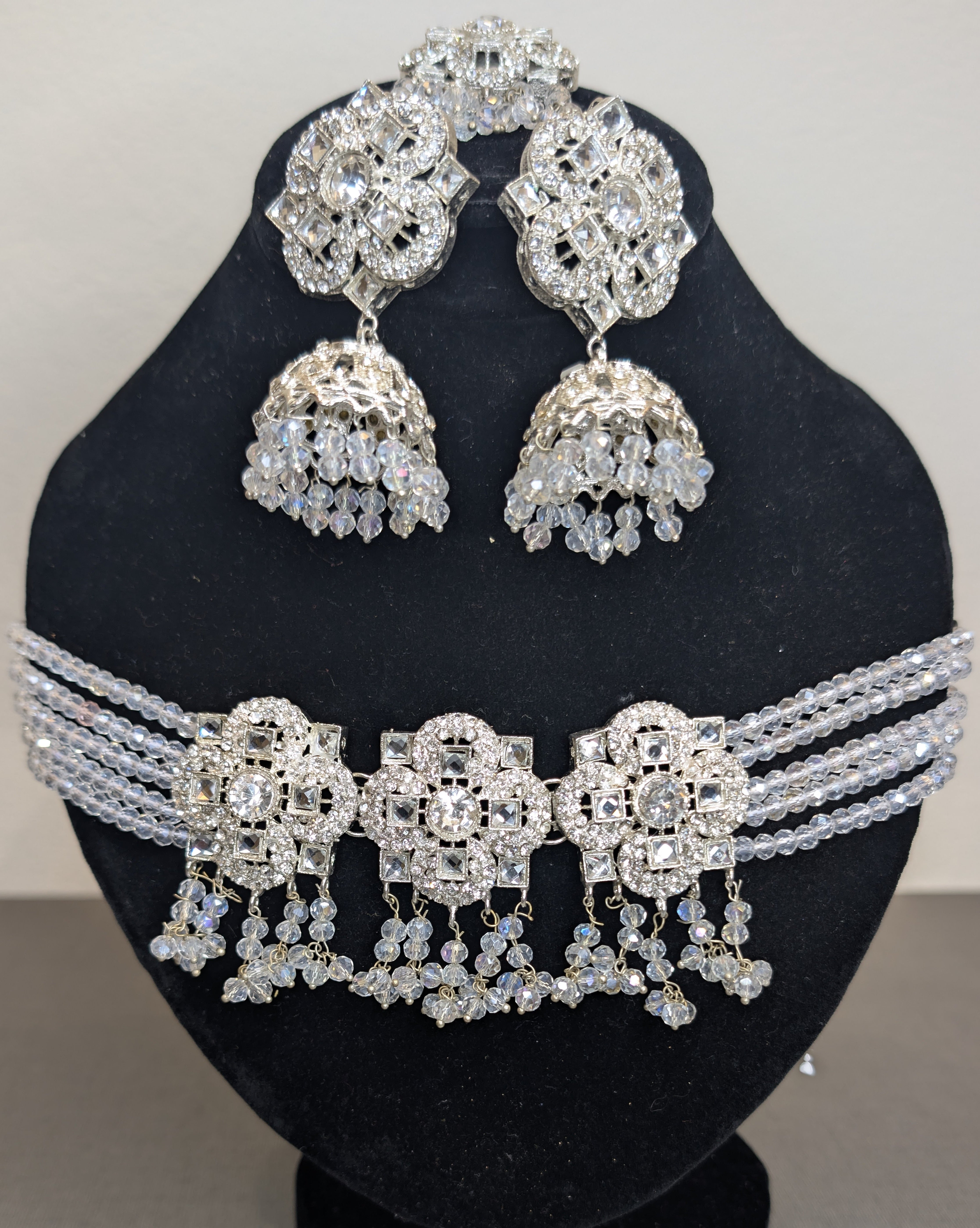 Silver jewelry set with earrings and a necklace on a black mannequin head.